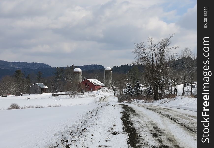 Barn and silos on farm road in Janurary with sun filtering onto snow covered barn and silos. Barn and silos on farm road in Janurary with sun filtering onto snow covered barn and silos.