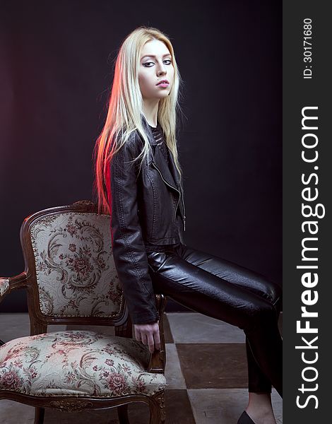 Beautiful girl sitting on a vintage chair studio shot