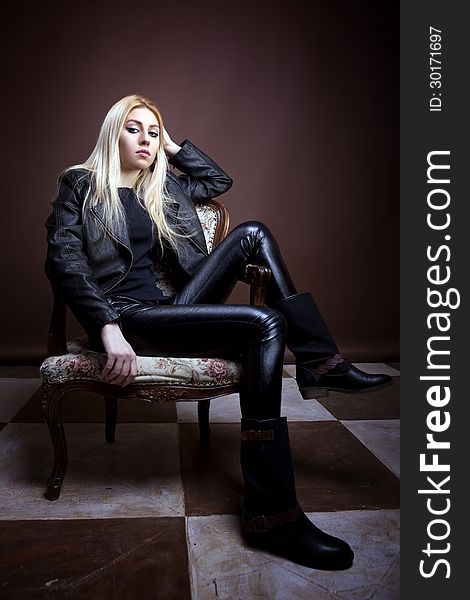 Gorgeous girl sitting on a vintage chair studio shot