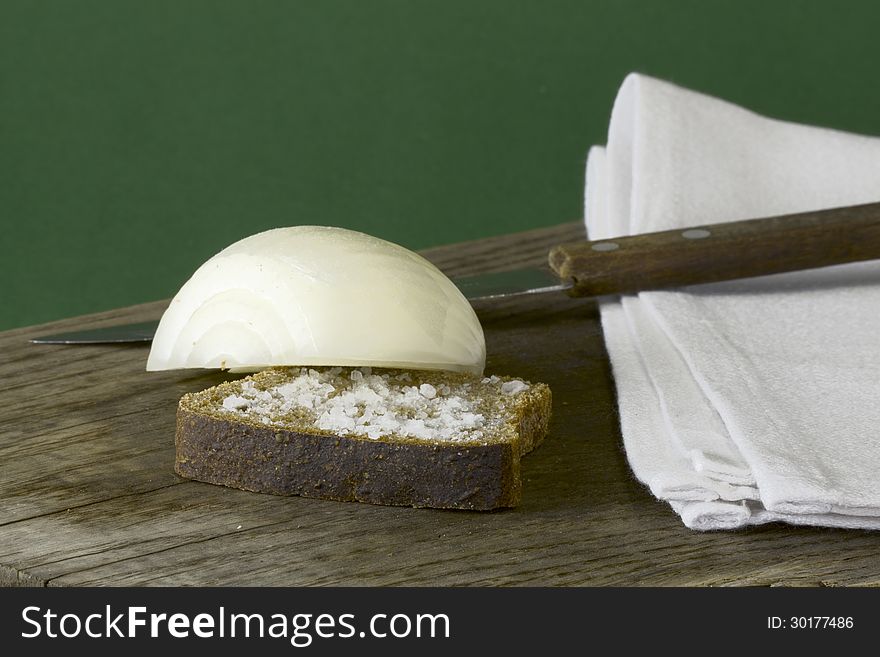 On the old wooden table rye bread with salt and the onions, green background