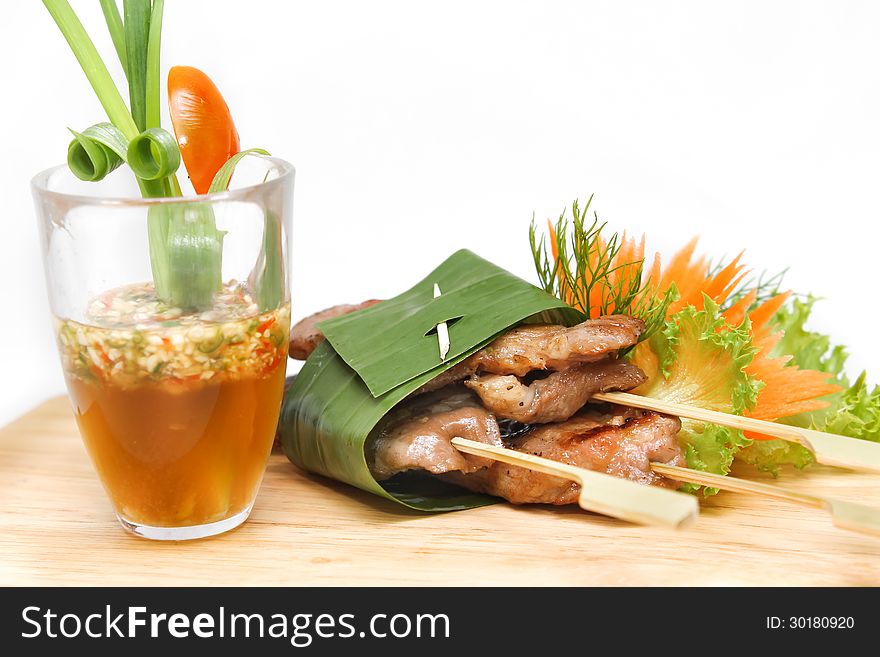 Roast pork wrapped in banana leaves and served with seafood sauce