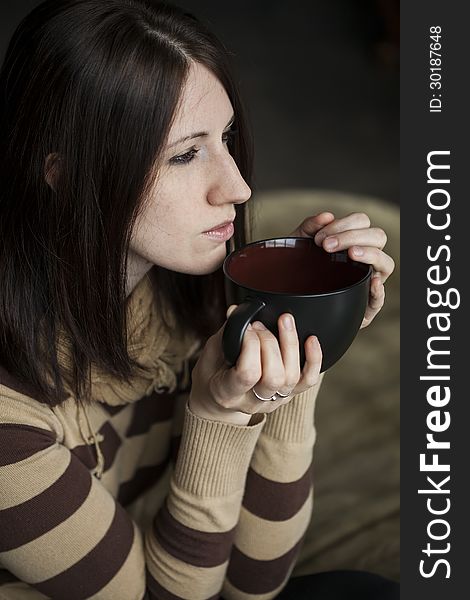 Beautiful young woman with brown hair and eyes holding a black coffee cup. Beautiful young woman with brown hair and eyes holding a black coffee cup.