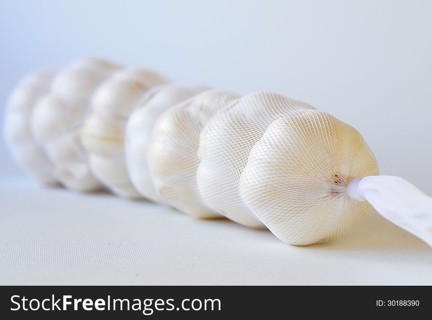 Seven fresh garlics in a bag on white background with copy space. Seven fresh garlics in a bag on white background with copy space.