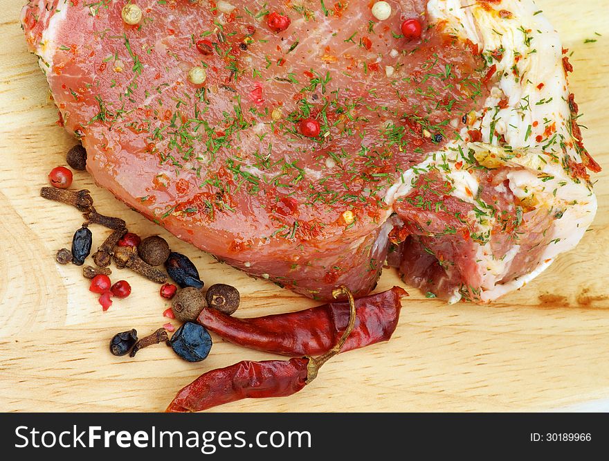 Marinated Raw Pork with Herbs, Greens and Spices closeup on Wooden Cutting Board