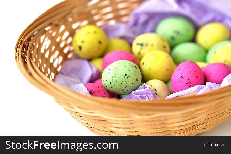 A basket made out of straws and containing vibrant colored eggs, for easter