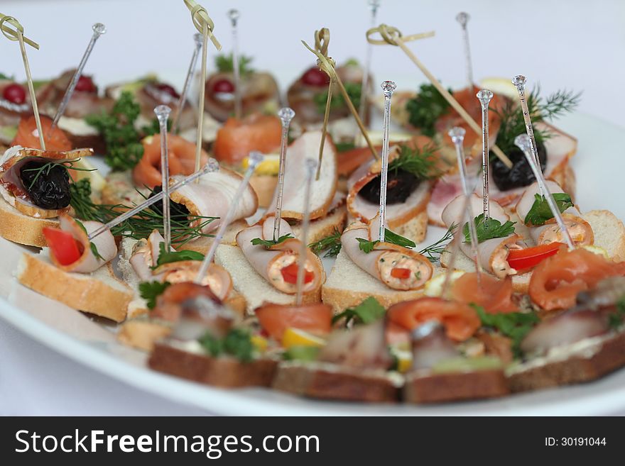 A lot of canapes with skewers and sandwiches