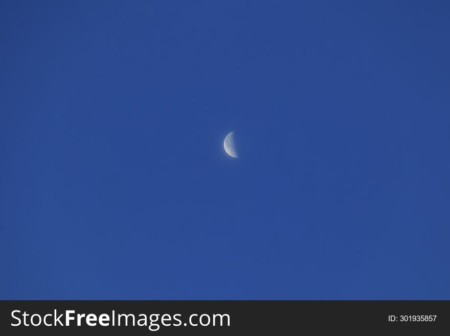 Moon in last quarter phase in dark blue clear sky.