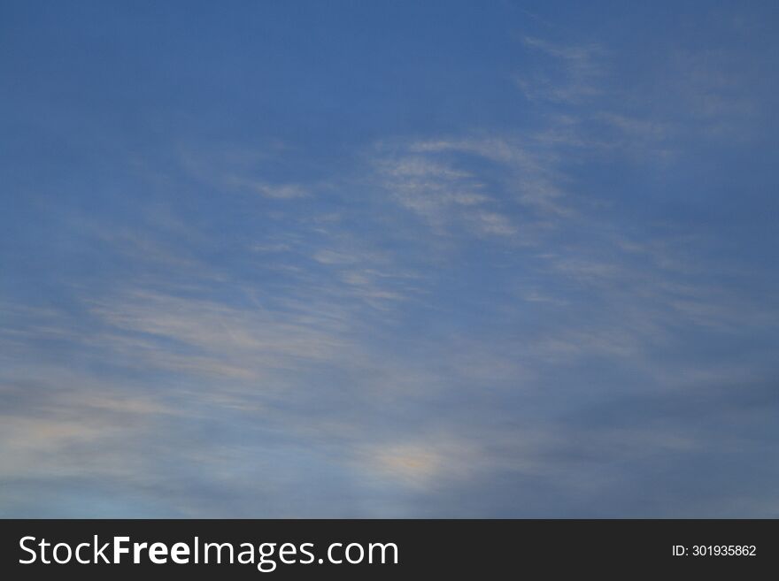 Cirrus and cumulus clouds in the dark blue sky on an early winter morning.