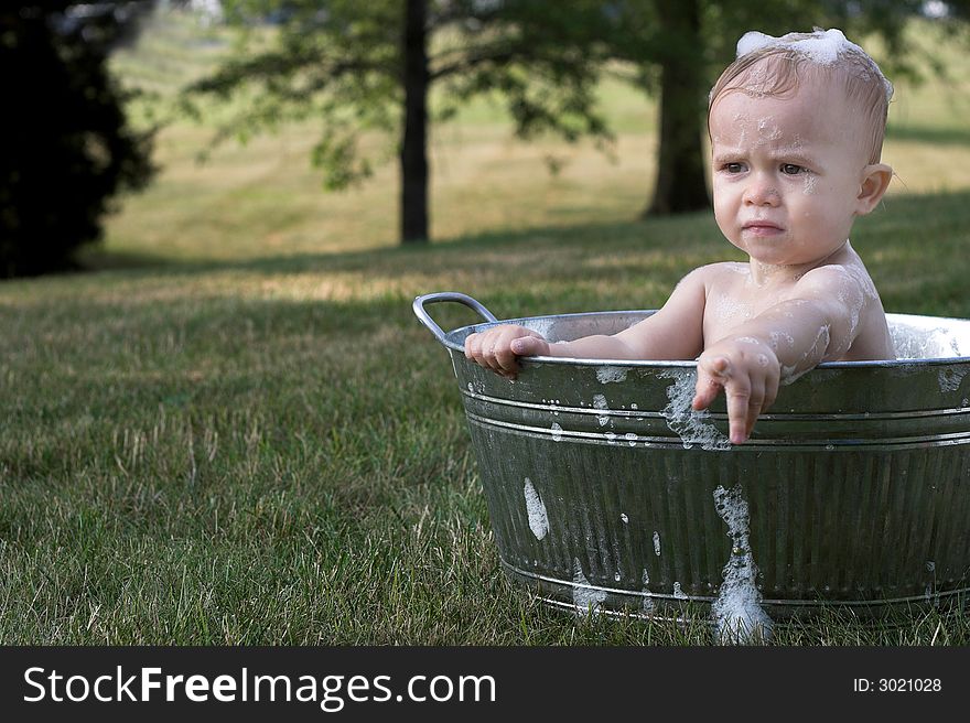 Image of cute toddler sitting in a tub outside. Image of cute toddler sitting in a tub outside