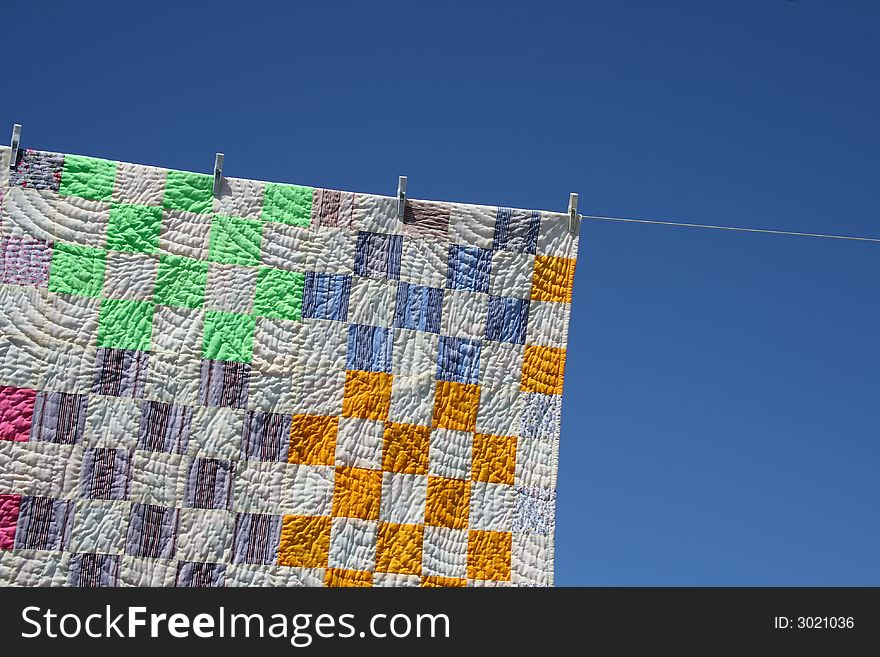 Laundry. Bright patchwork counterpane hanging to dry on a clothes-line.