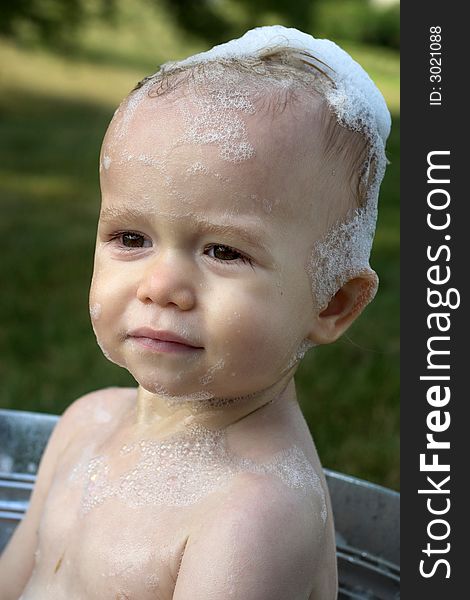 Image of cute toddler sitting in a tub outside. Image of cute toddler sitting in a tub outside