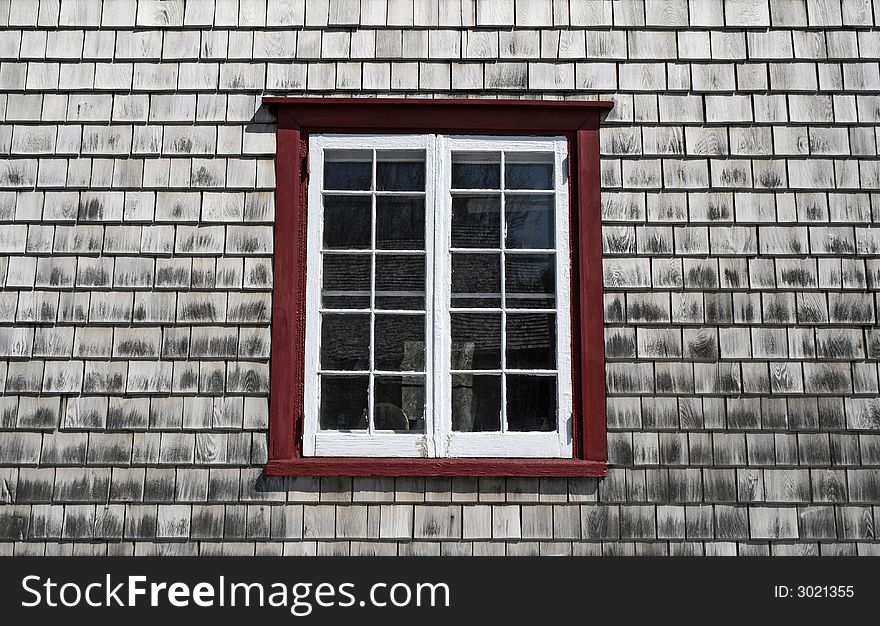 Window of an old country house with wooden tiled walls.