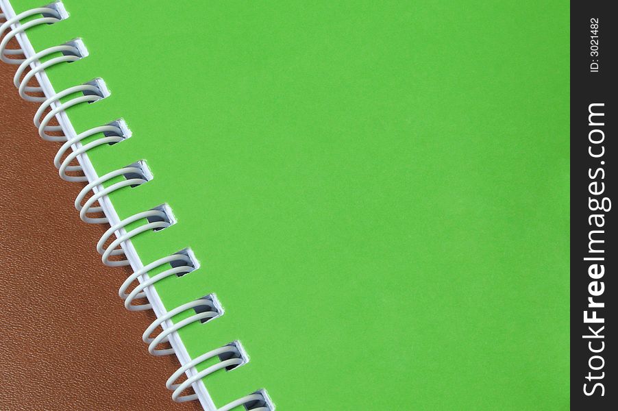 A green cover of a spiral notebook on a leather background