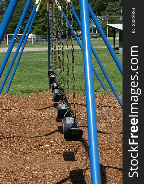 A blue swing set on a playground in the park. A blue swing set on a playground in the park