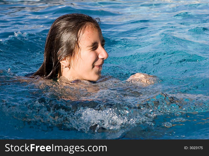 Young girl in the swimming pool getting up for air. Splashes of water. Eyes are closed. Young girl in the swimming pool getting up for air. Splashes of water. Eyes are closed.