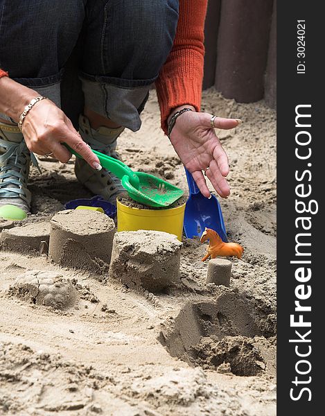 Woman making sand shapes with toy molds and plastic shovel. Woman making sand shapes with toy molds and plastic shovel