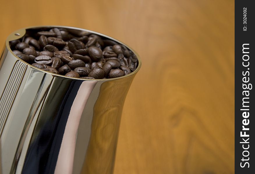 A coffee grinder with beans on a wooden table
