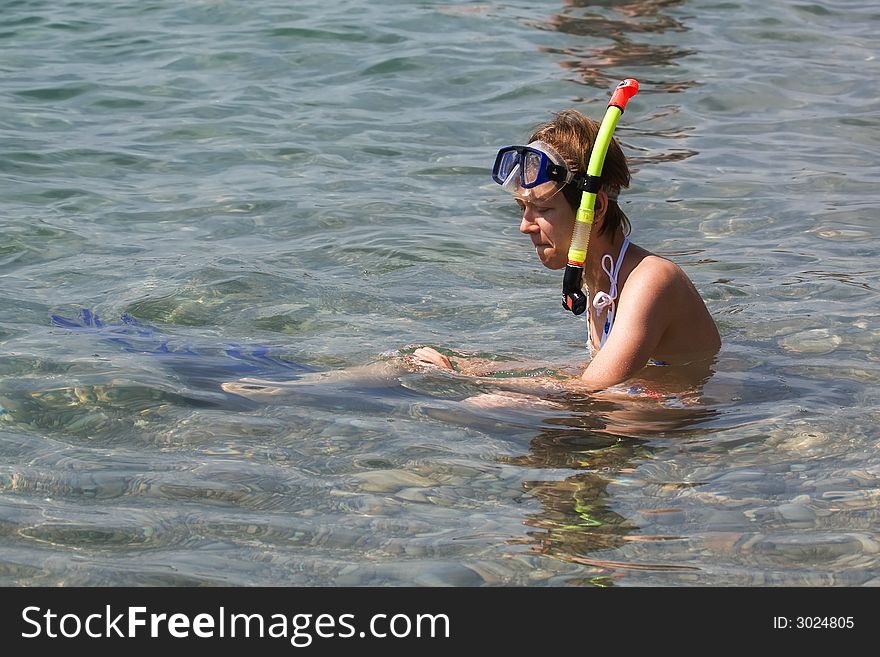Young woman sitting in water with snorkel and fins