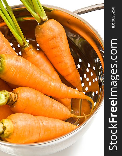 Fresh carrots in the colander on white background