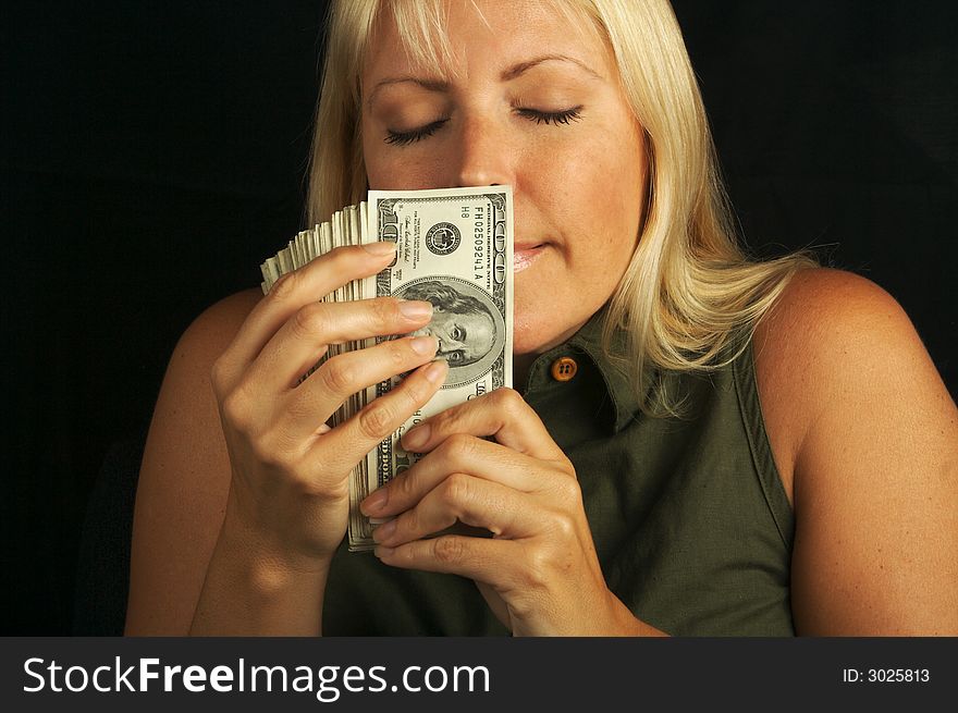 Attractive Woman Smelling her Stack of Money on a Black Background. Attractive Woman Smelling her Stack of Money on a Black Background