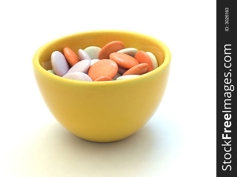 Colorful candy in yellow cup on white background