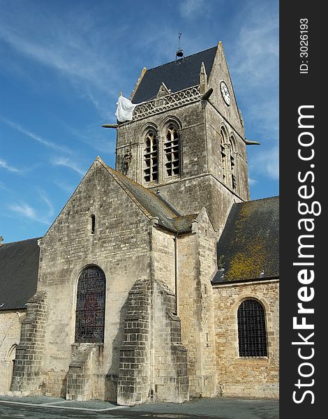 Sainte Mere Eglise was the first town liberated by the Allies just before H-Hour on D-Day. The town was the scene of a famous incident where American paratrooper John Steele had his parachute caught on the spire of the church. There is a dummy and parachute hanging on the church to commemorate this story (Normandy - France). Sainte Mere Eglise was the first town liberated by the Allies just before H-Hour on D-Day. The town was the scene of a famous incident where American paratrooper John Steele had his parachute caught on the spire of the church. There is a dummy and parachute hanging on the church to commemorate this story (Normandy - France)