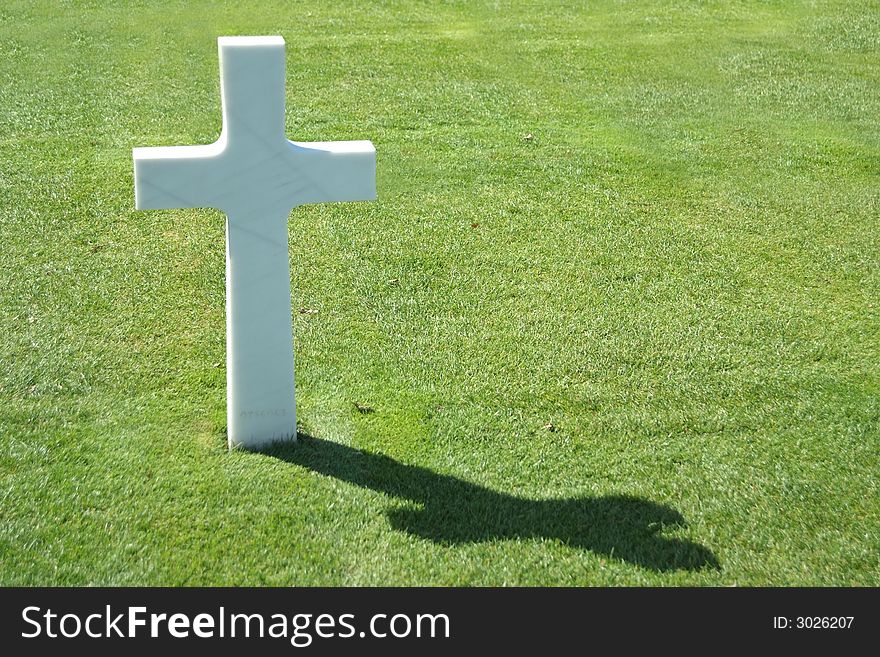 A simple cross standing in backlight against a lush green lawn. A simple cross standing in backlight against a lush green lawn.