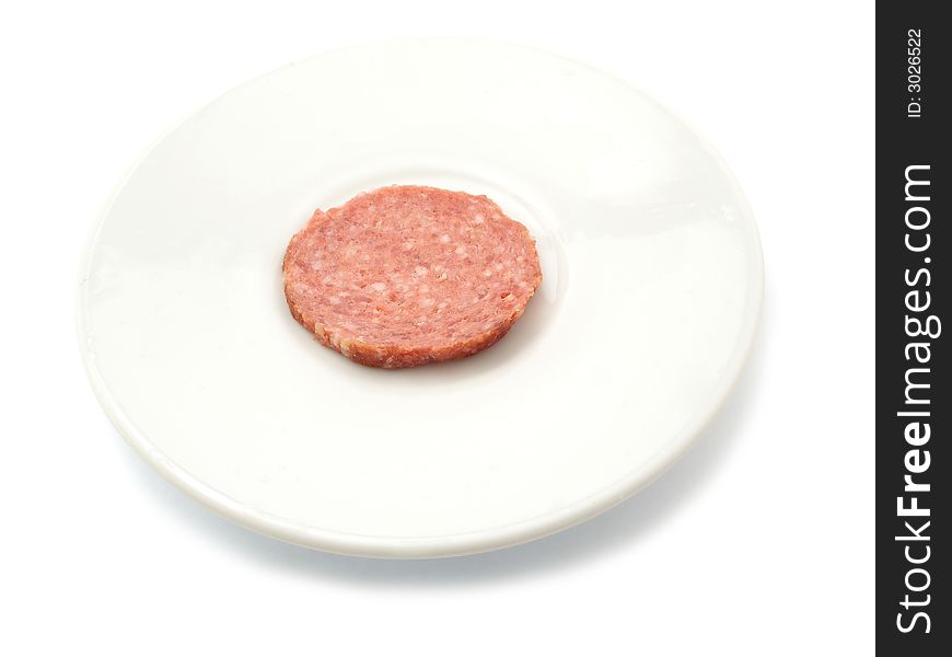 One sliece of smoked sausage on a plate. isolated on white.