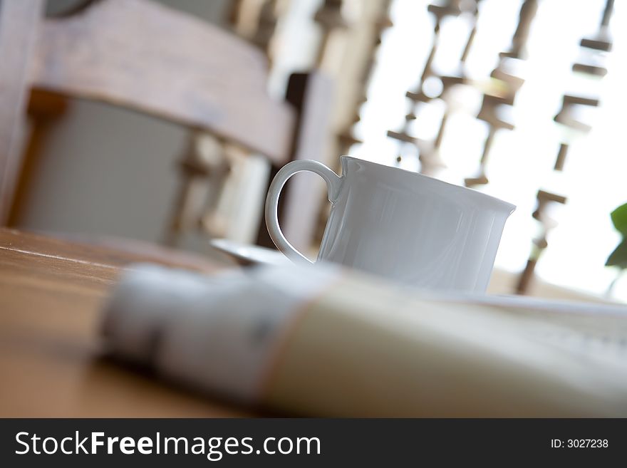 Cup of coffee and newspaper on kitchen table. Cup of coffee and newspaper on kitchen table
