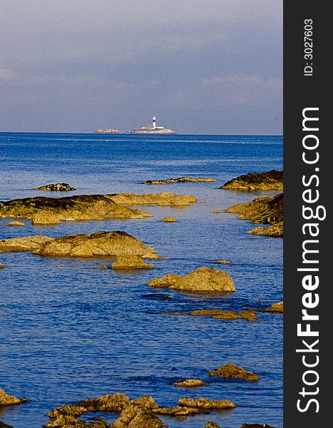 Rockabill Lighthouse, Skerries, Dublin, Ireland with rocks and ocean in the foreground.