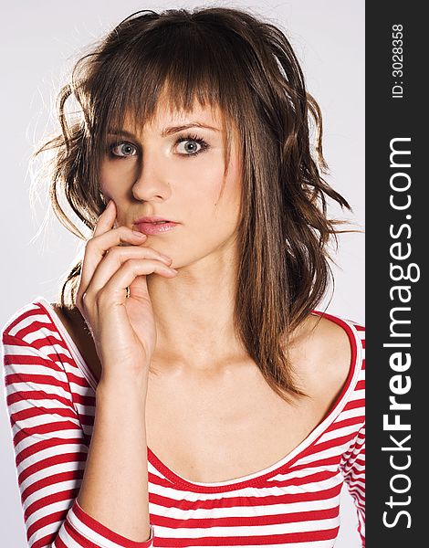 Brunette woman on light background wearing red and white striped blouse