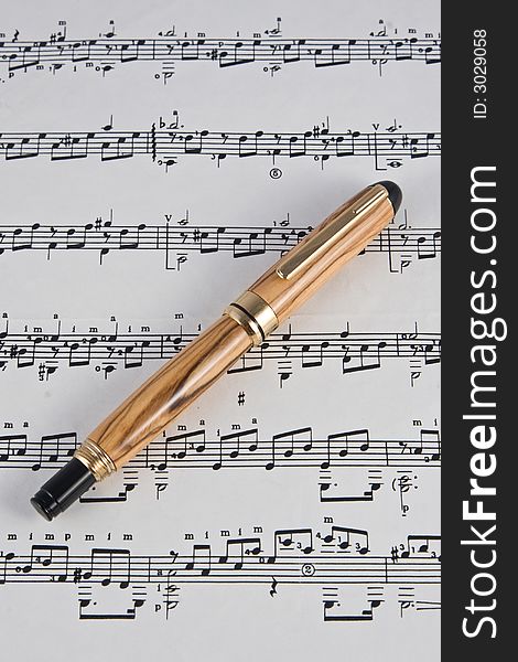 A handmade fine writing instrument made from Bethlehem Olive Wood displayed on a sheet of music. (The pen was handmade by the photographer in his studio).