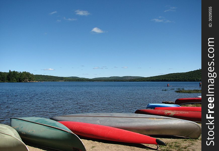 Canoes on a beach with a view of the lake of two rivers in Algonquin Park.