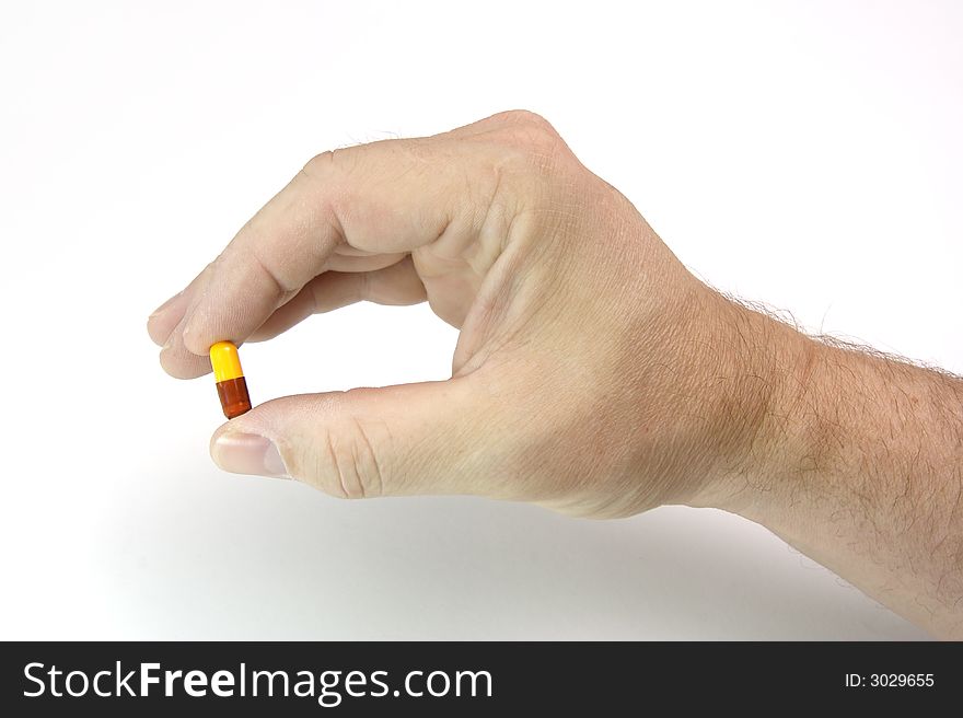 Male hand holding a two-colored pill for medicine. Male hand holding a two-colored pill for medicine.