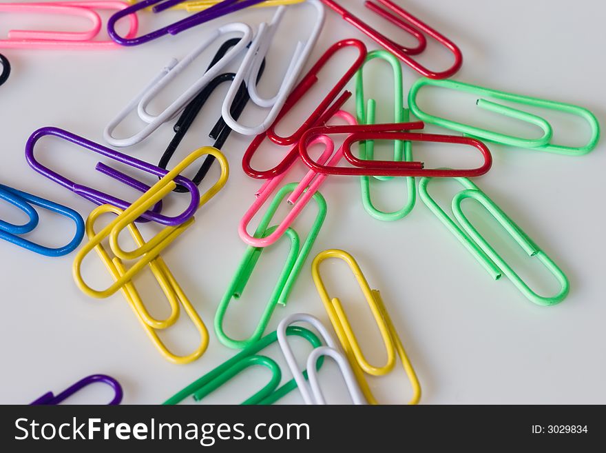 Multi-coloured paper clips on a white table.