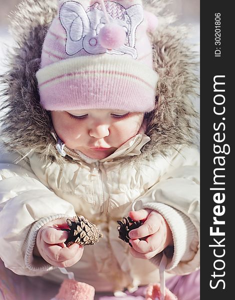 Winter outdoor portrait of little girl playing with cones. Winter outdoor portrait of little girl playing with cones