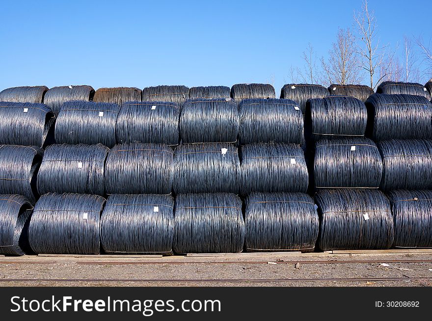 Stacked rows of newly manufactured steel wire coils. Stacked rows of newly manufactured steel wire coils.