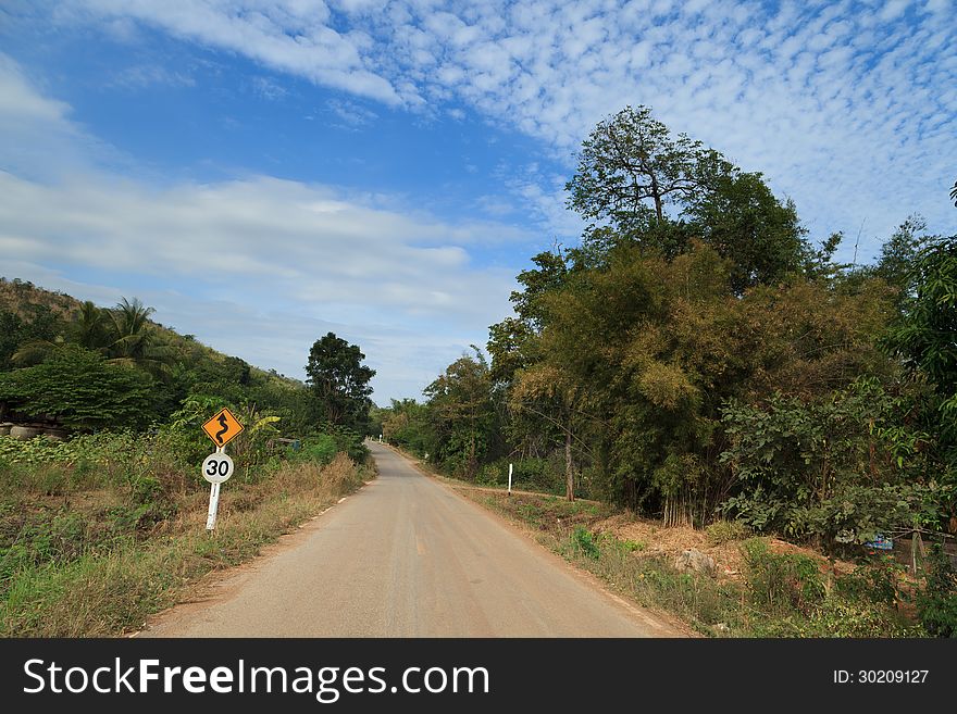 Country road in a rural area with a traffic sign (speed limit 30 km/hr) in Thailand