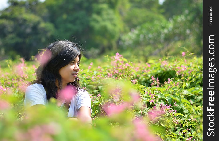 Young Woman Sitting In Green Rural Field