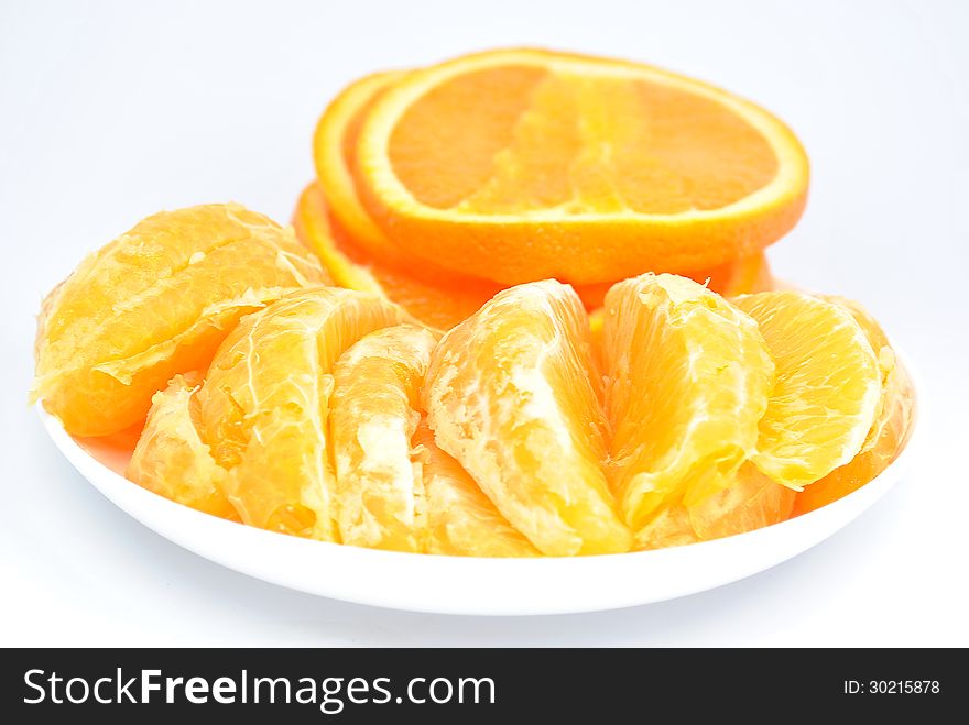 Pieces of orange on the plate and on a white background. Pieces of orange on the plate and on a white background