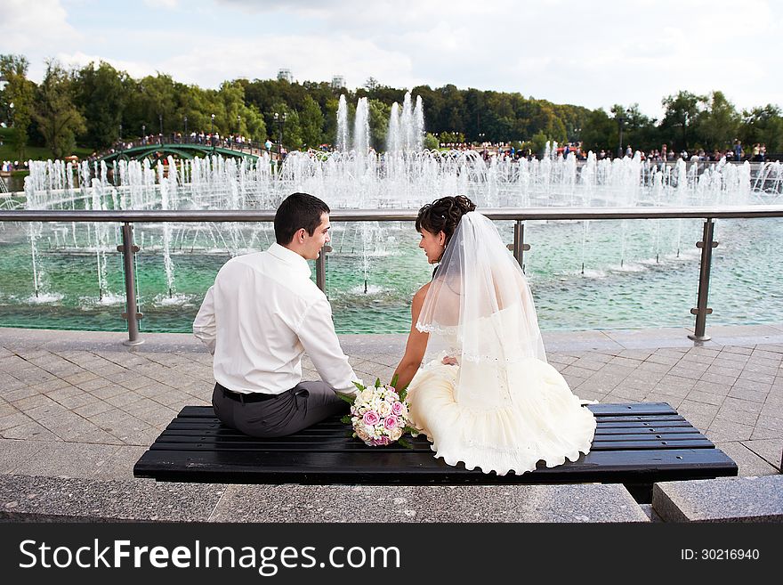 Happy bride and groom near fountain