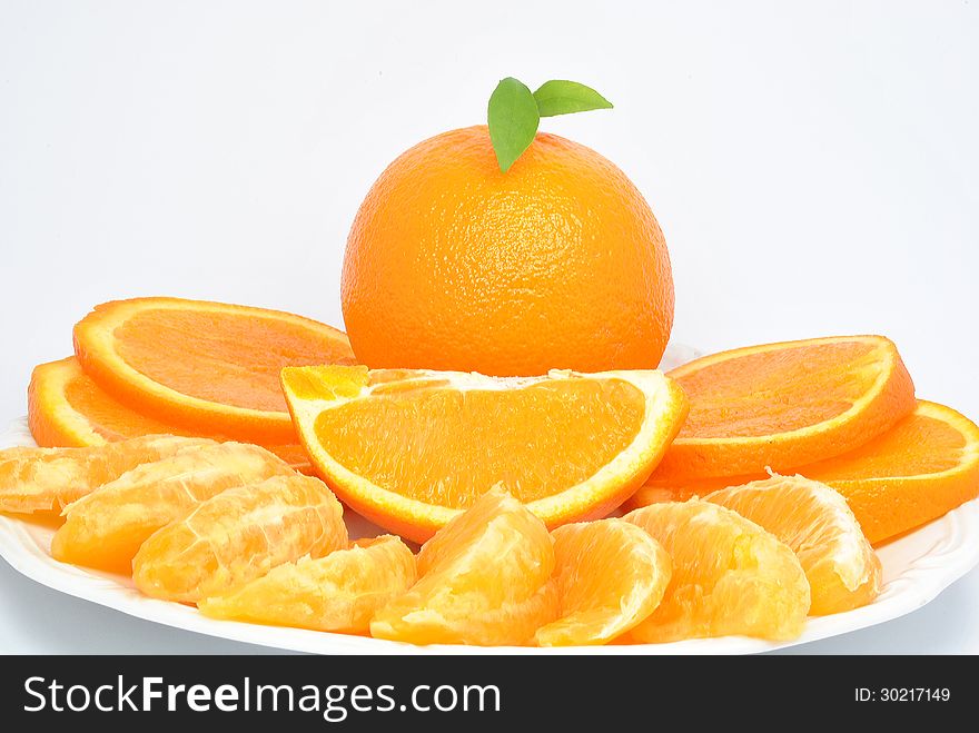 Orange and orange pieces on a plate and white background. Orange and orange pieces on a plate and white background