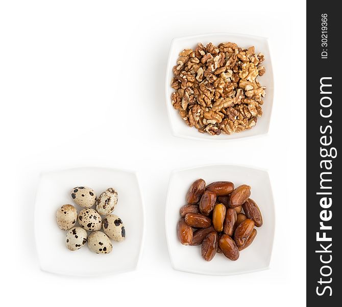 On the white table there are plates of walnuts, quail eggs and dates. You can put your text on free space in the upper left part of the picture. On the white table there are plates of walnuts, quail eggs and dates. You can put your text on free space in the upper left part of the picture.