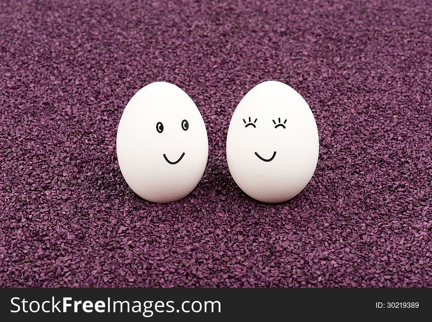 Two white eggs on purple sand smile at each other. Two white eggs on purple sand smile at each other.