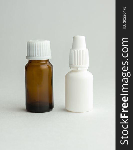 Small bottle from dark glass with a white cover and tablets. Small bottle from dark glass with a white cover and tablets.