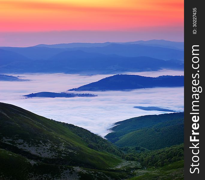 Landscape with bright dawn in the mountains. Morning clouds below the mountains. Landscape with bright dawn in the mountains. Morning clouds below the mountains