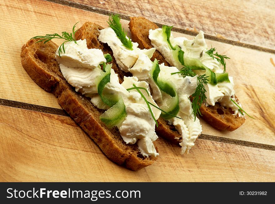 Cream Cheese Sandwiches with Chives, Cucumber, Dill and Whole Wheat Bread closeup on Wooden background