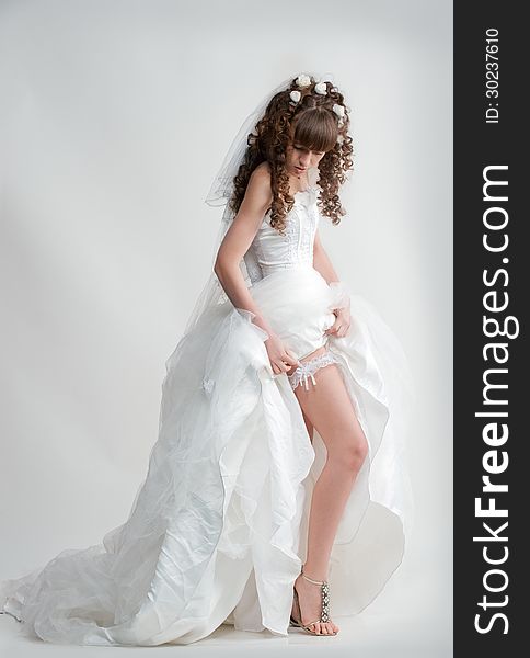 Photo in full height leggy elegant model in a beautiful wedding dress posing in studio. Photo in full height leggy elegant model in a beautiful wedding dress posing in studio