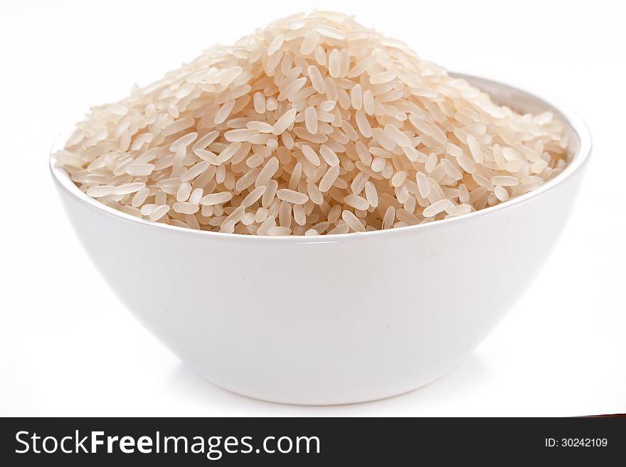 Uncooked rice in a bowl on a white background. Uncooked rice in a bowl on a white background.