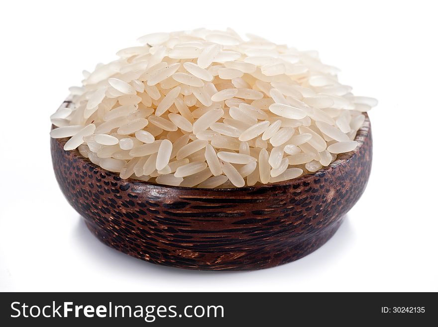 Uncooked rice in a wooden bowl on a white background. Uncooked rice in a wooden bowl on a white background.